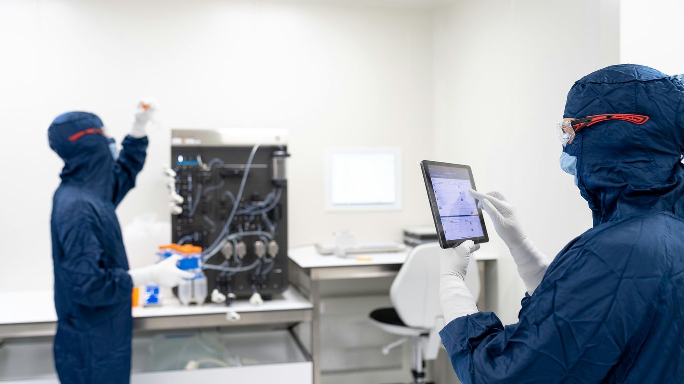 a couple of people in blue protective gear in front of a computer