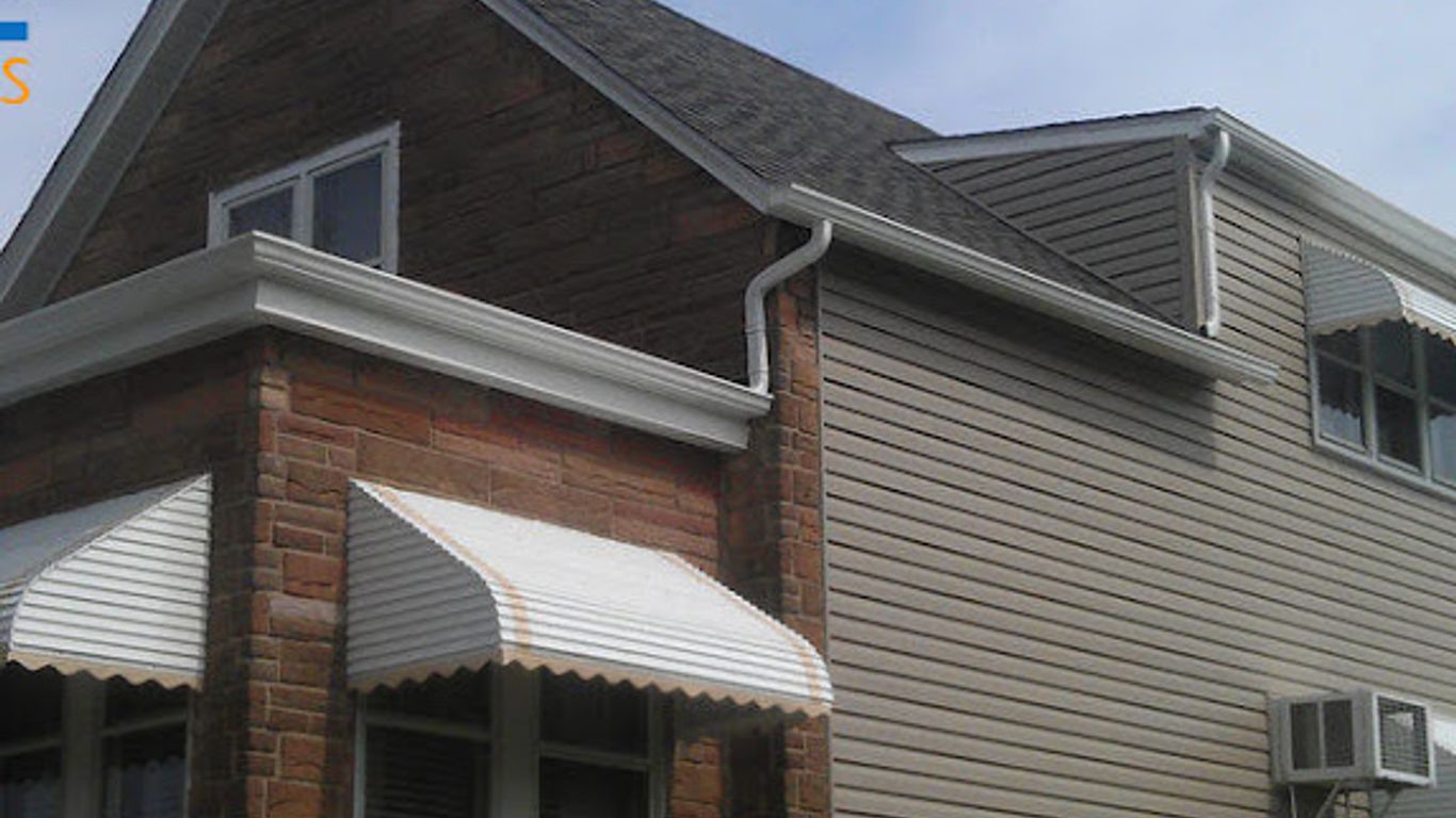 A house with awnings over the windows and siding on the exterior.