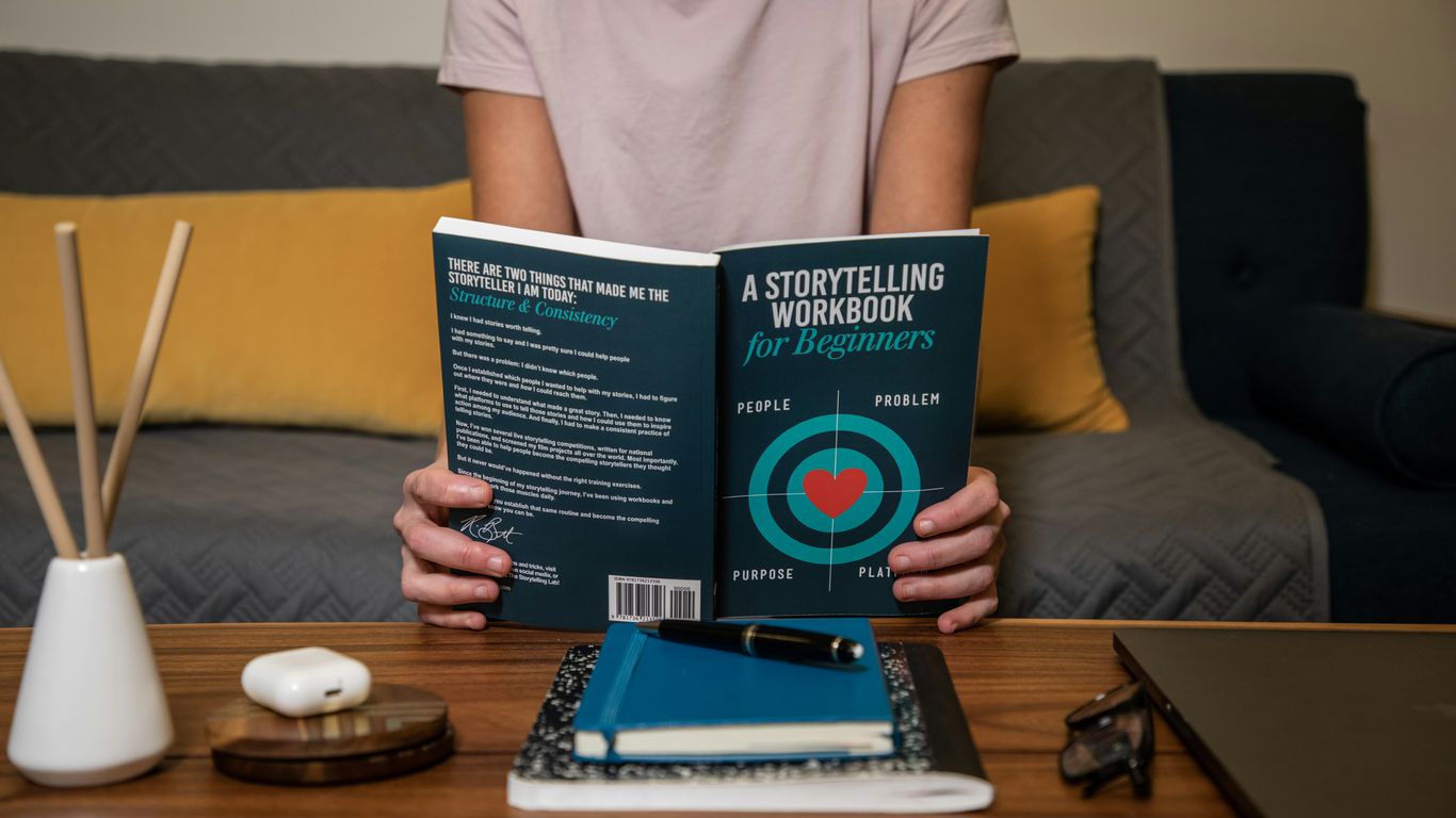 man in white crew neck t-shirt holding blue book