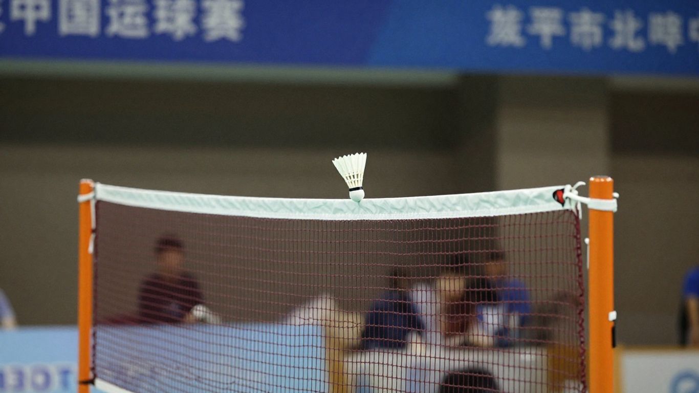 Badminton net with shuttlecock flying over it.