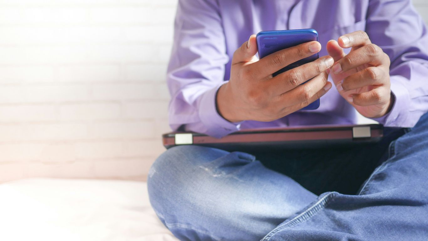 man in white dress shirt and blue denim jeans sitting on bed
