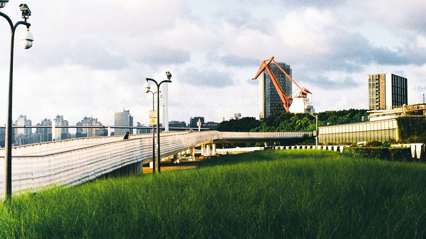 Modern city skyline with lush green grass in foreground.