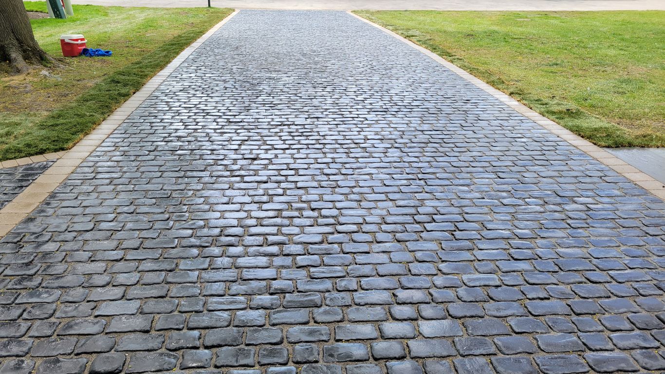 A newly paved cobblestone driveway with trucks in the background.