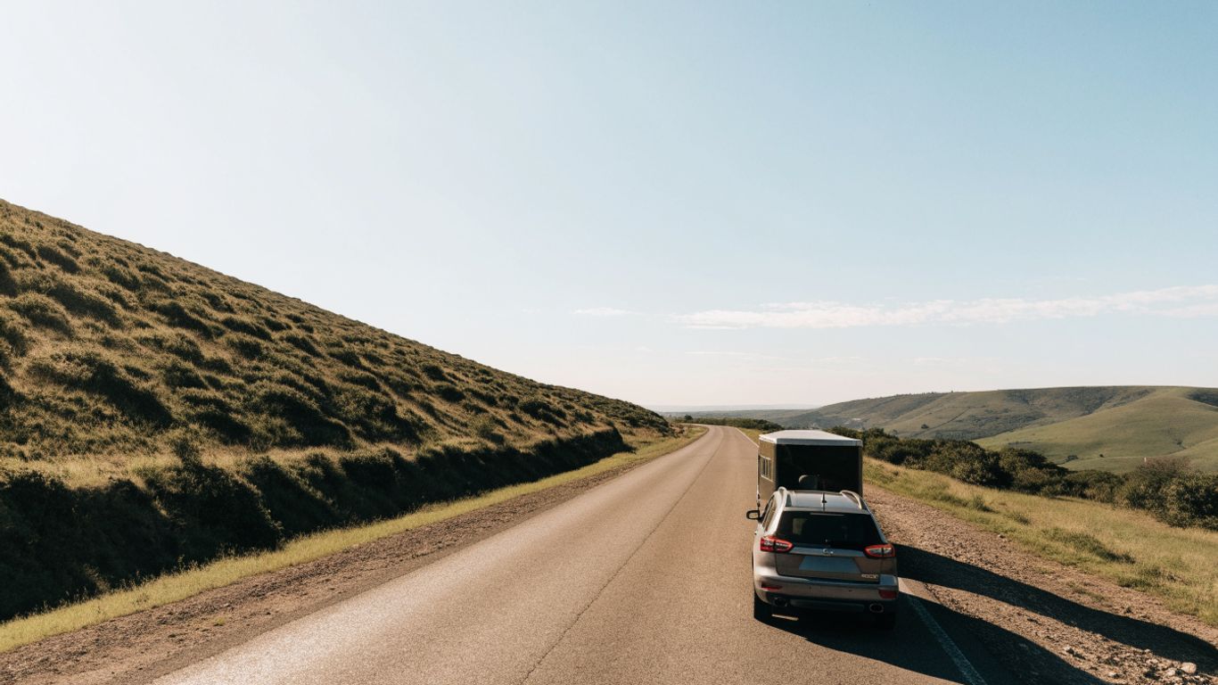 A vehicle towing a small trailer on a sunny road
