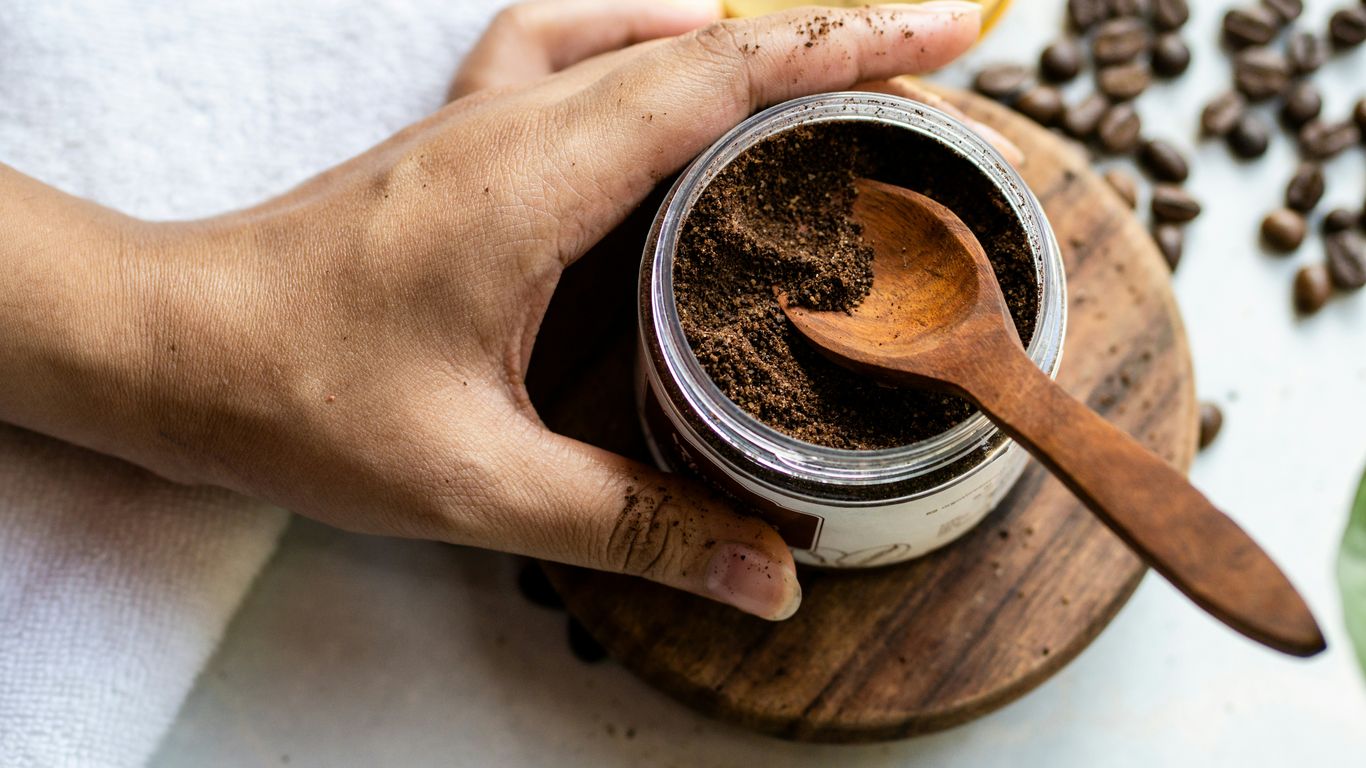 a person holding a wooden spoon over a jar of coffee