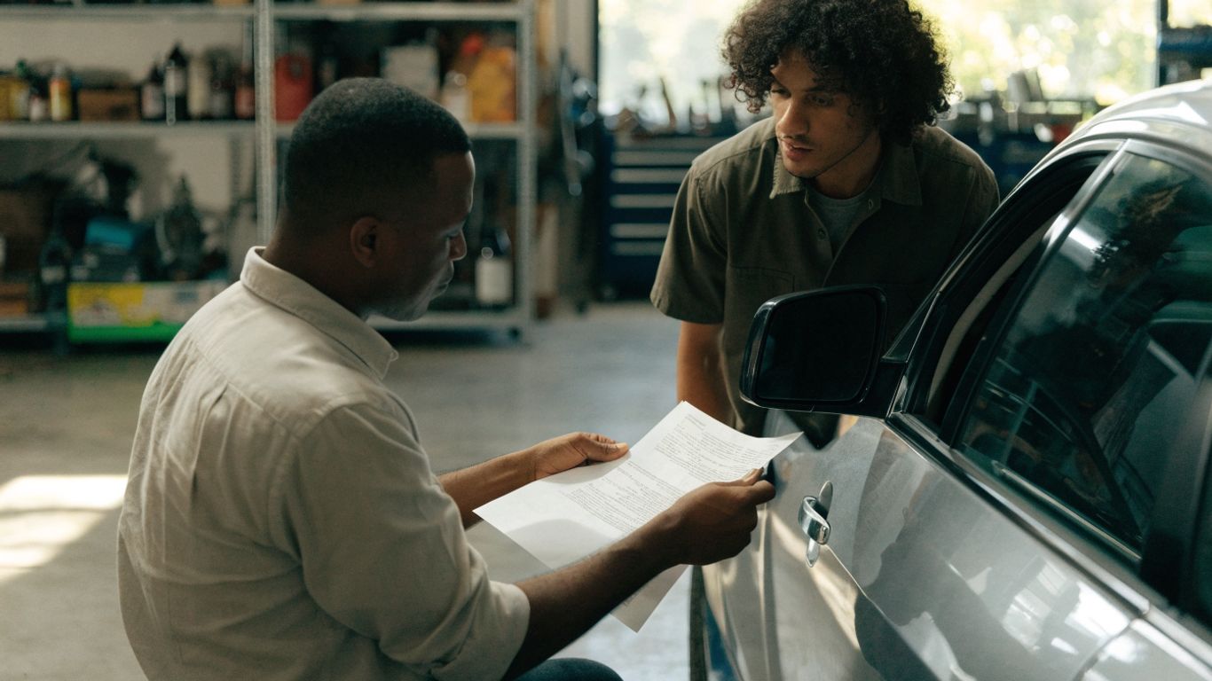 Written service estimate beside a car in a repair bay