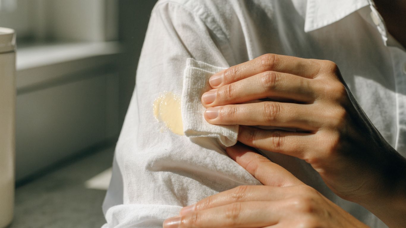 Hands blotting sunscreen from white cotton fabric
