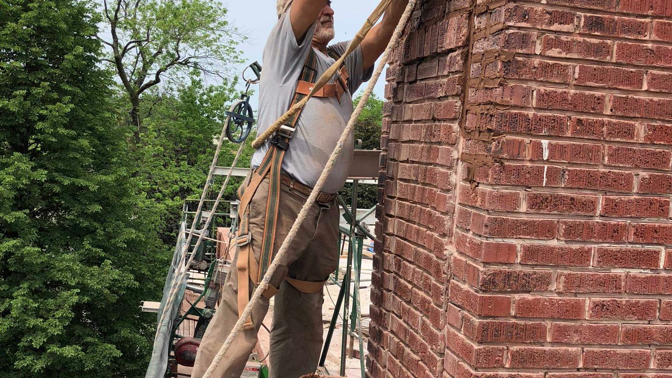 A person works on a brick chimney from scaffolding.