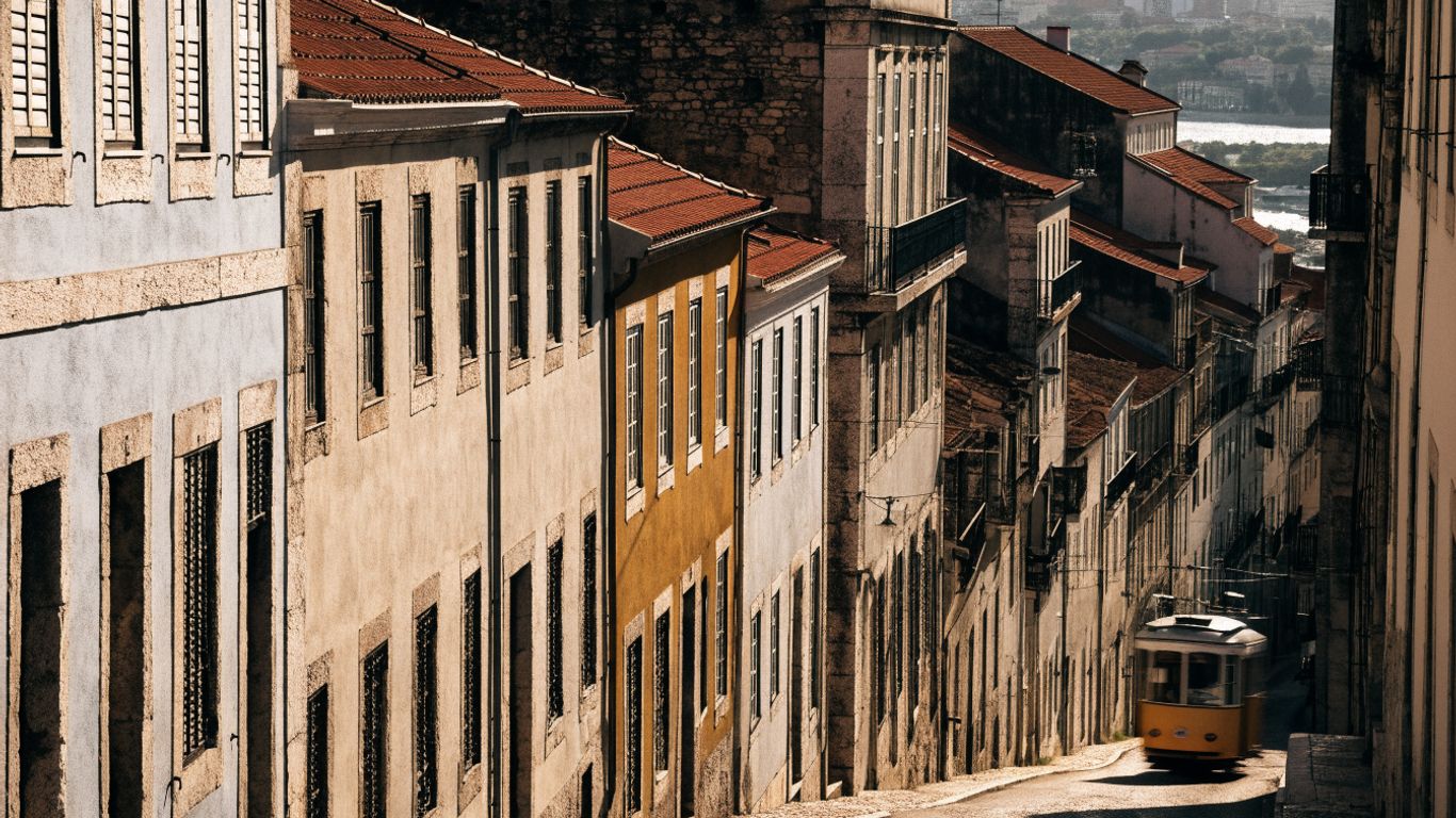 Lisbon rooftops and a tram winding through a hillside street