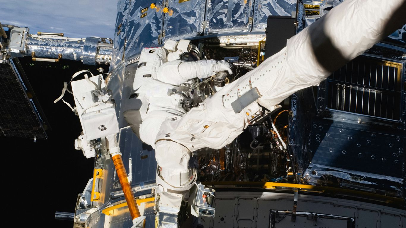 a man in a white space suit is outside of a space station