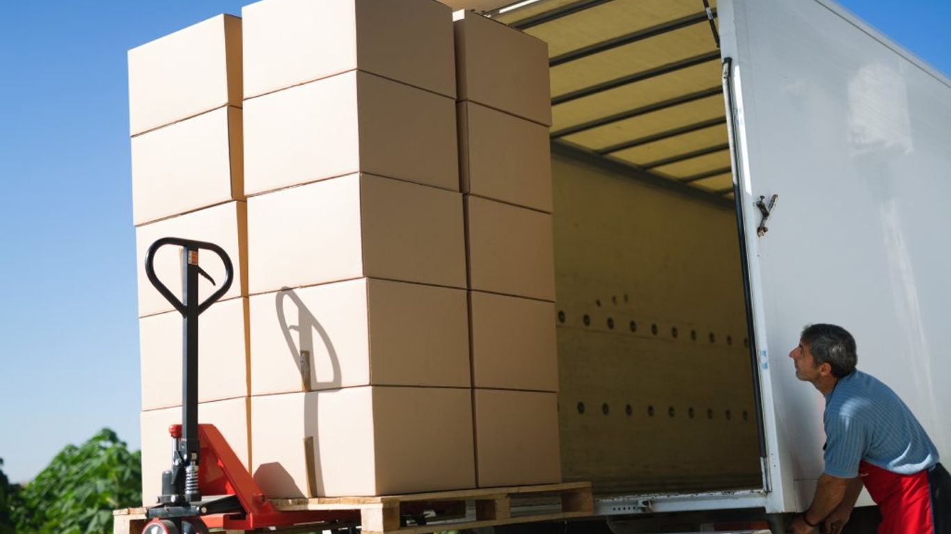 Man loading boxes onto a truck with a pallet jack.