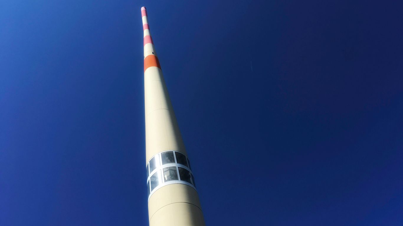 a tall white tower with a red and white stripe on it
