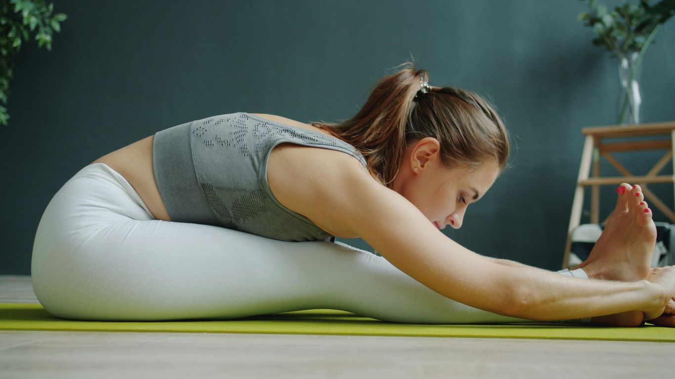 Woman stretching on a yoga mat indoors.