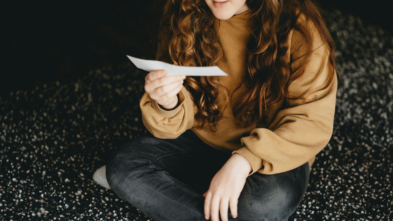 woman in brown long sleeve shirt and blue denim jeans sitting on black and white textile