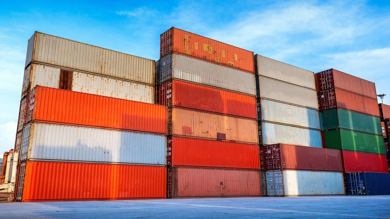 Stacks of colorful shipping containers under a bright blue sky.