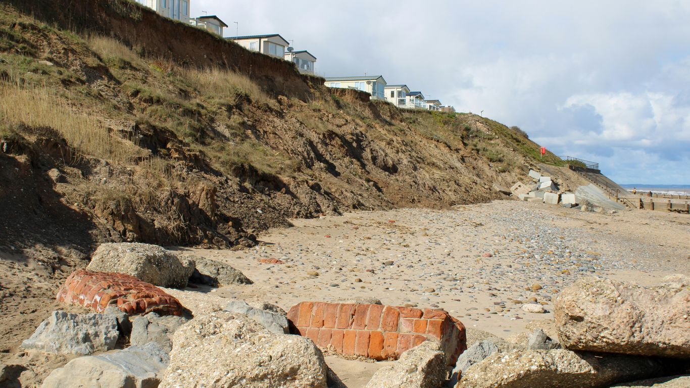a beach with rocks and a hill