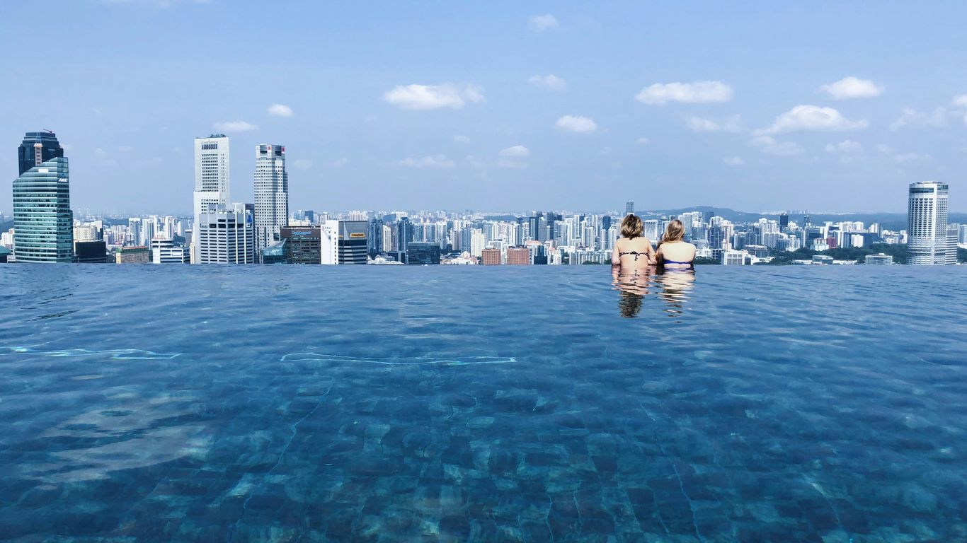 two women's swimming in pool while looking at building