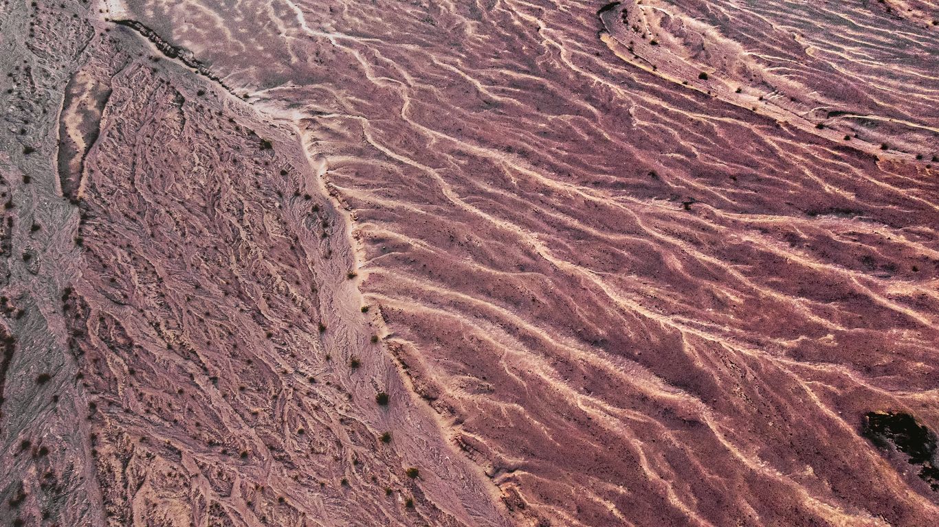 A sleek white drone flying over a vast desert