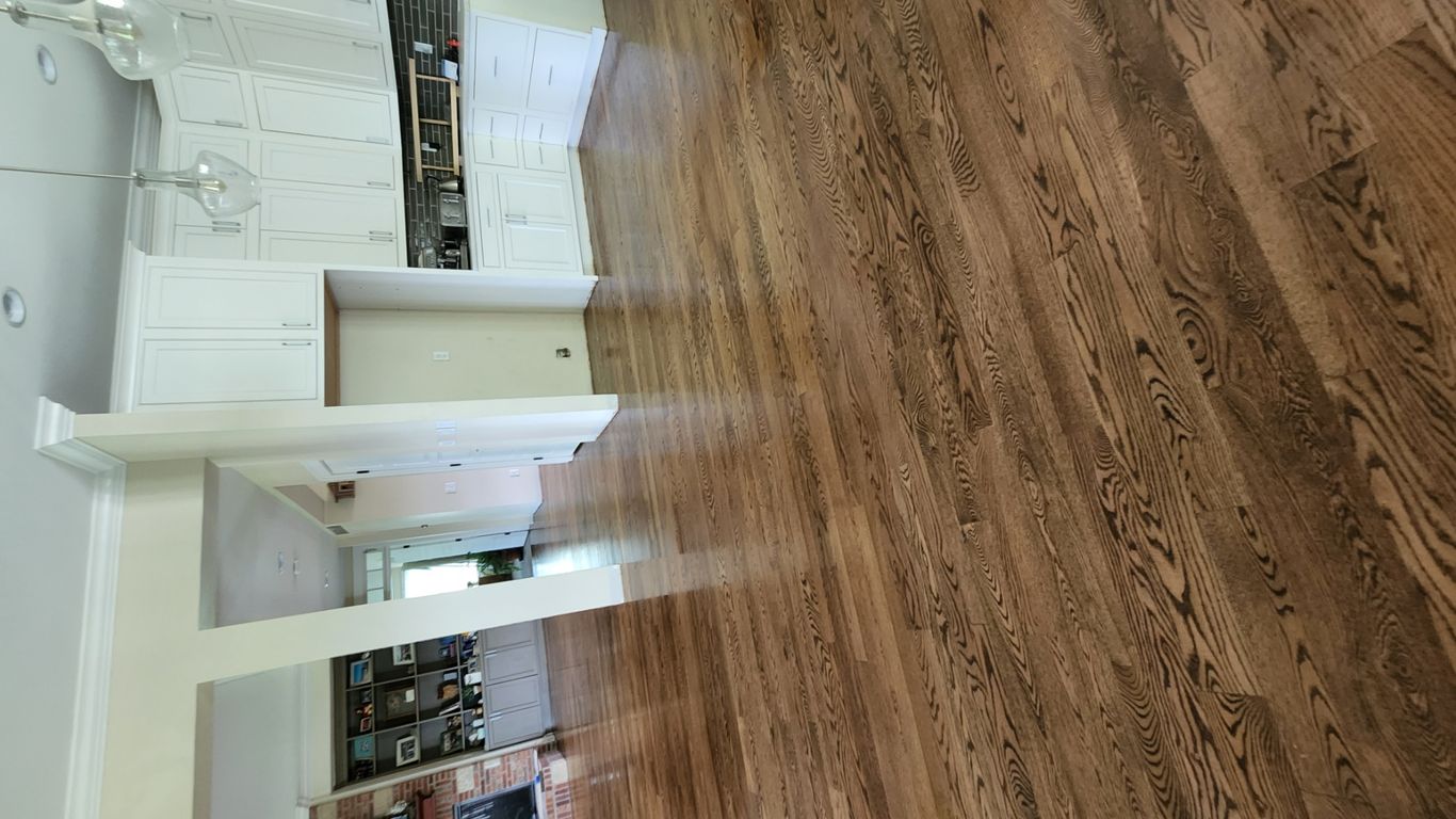 Spacious open floor plan with wooden flooring and modern kitchen.