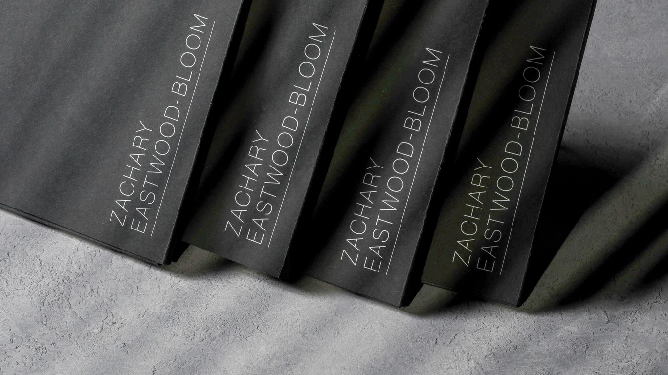 A group of three black books sitting on top of a bed