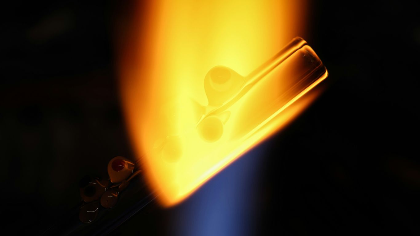 a close up of a piece of metal with a flame in the background