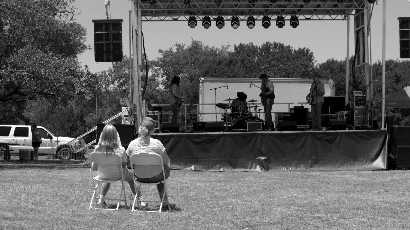 People watch a band performing on an outdoor stage.