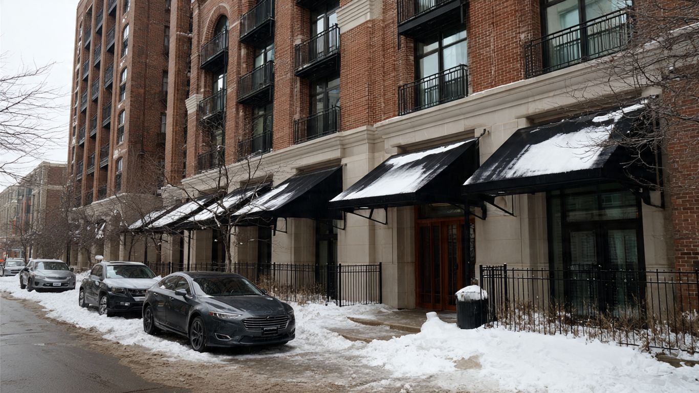 Cars parked on a snowy street in front of a brick building.