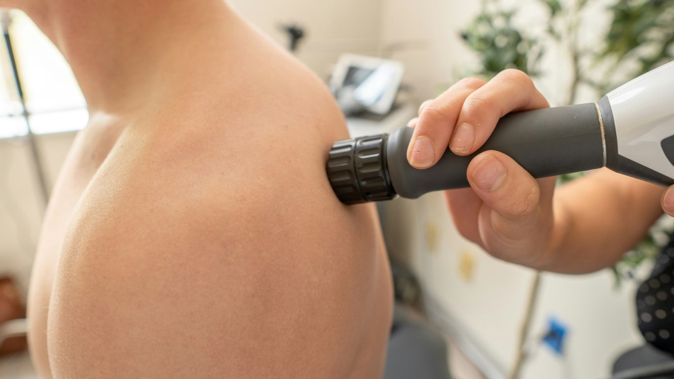 doctor examining patient with shockwave therapy device