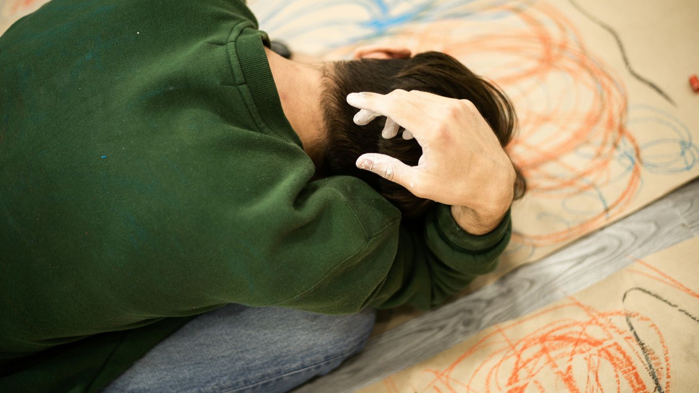 man in green sweater lying on bed