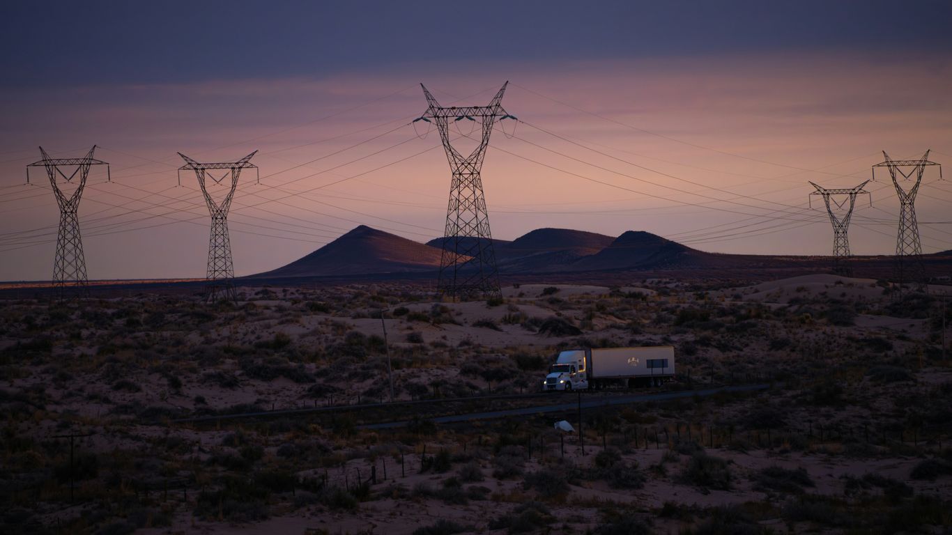 Power lines and truck in desolate landscape at dusk