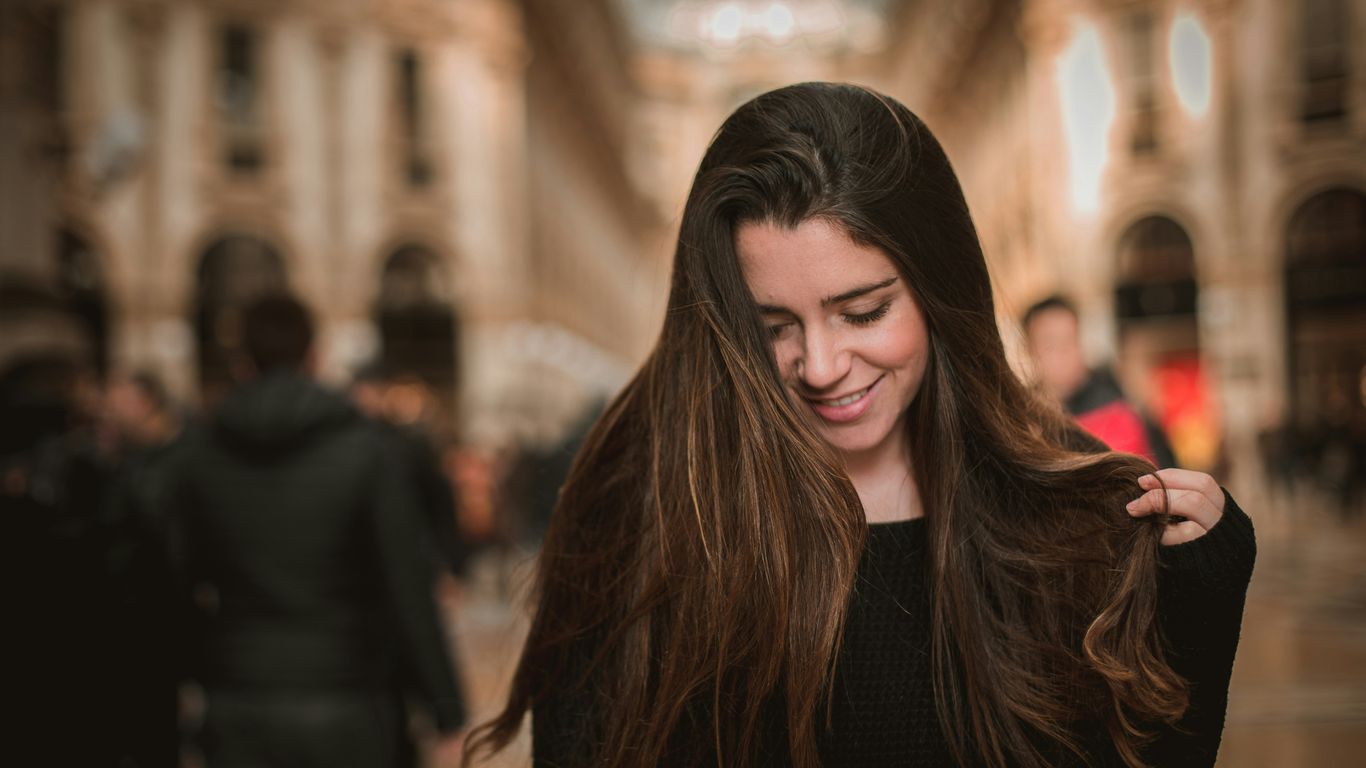 smiling woman holding her hair looking on ground