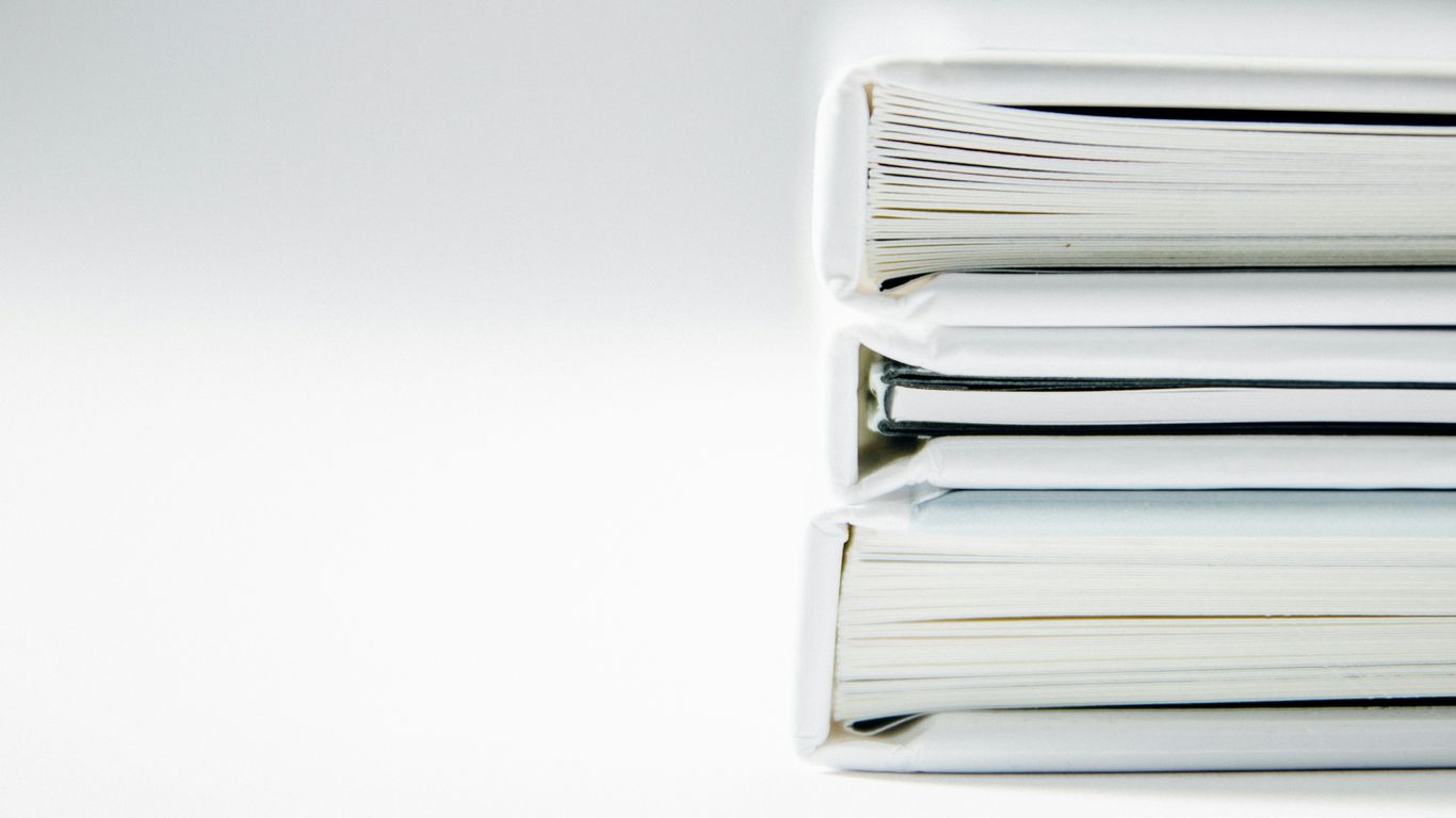 A stack of thick folders on a white surface