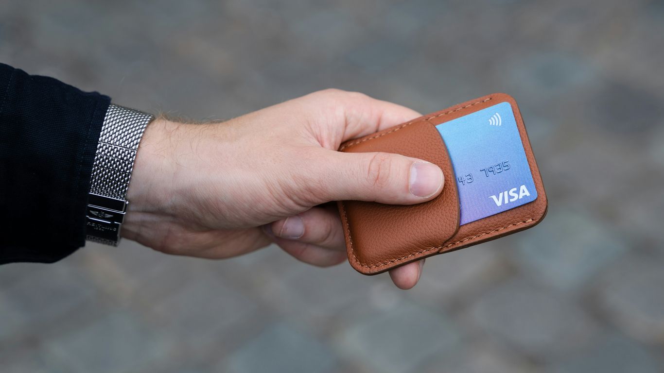 a hand holding a wallet with a credit card in it