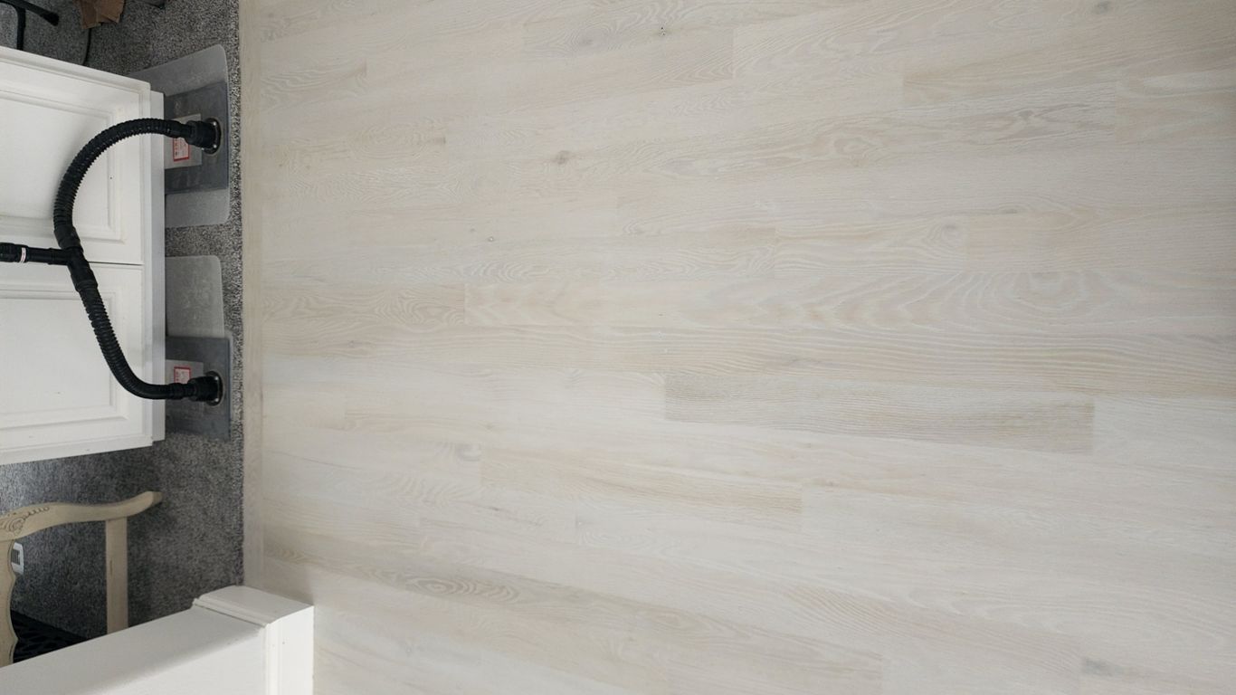 Light-colored wooden floor with a transition to another area.