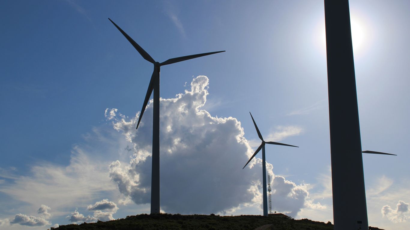 a group of windmills on a hill under a blue sky