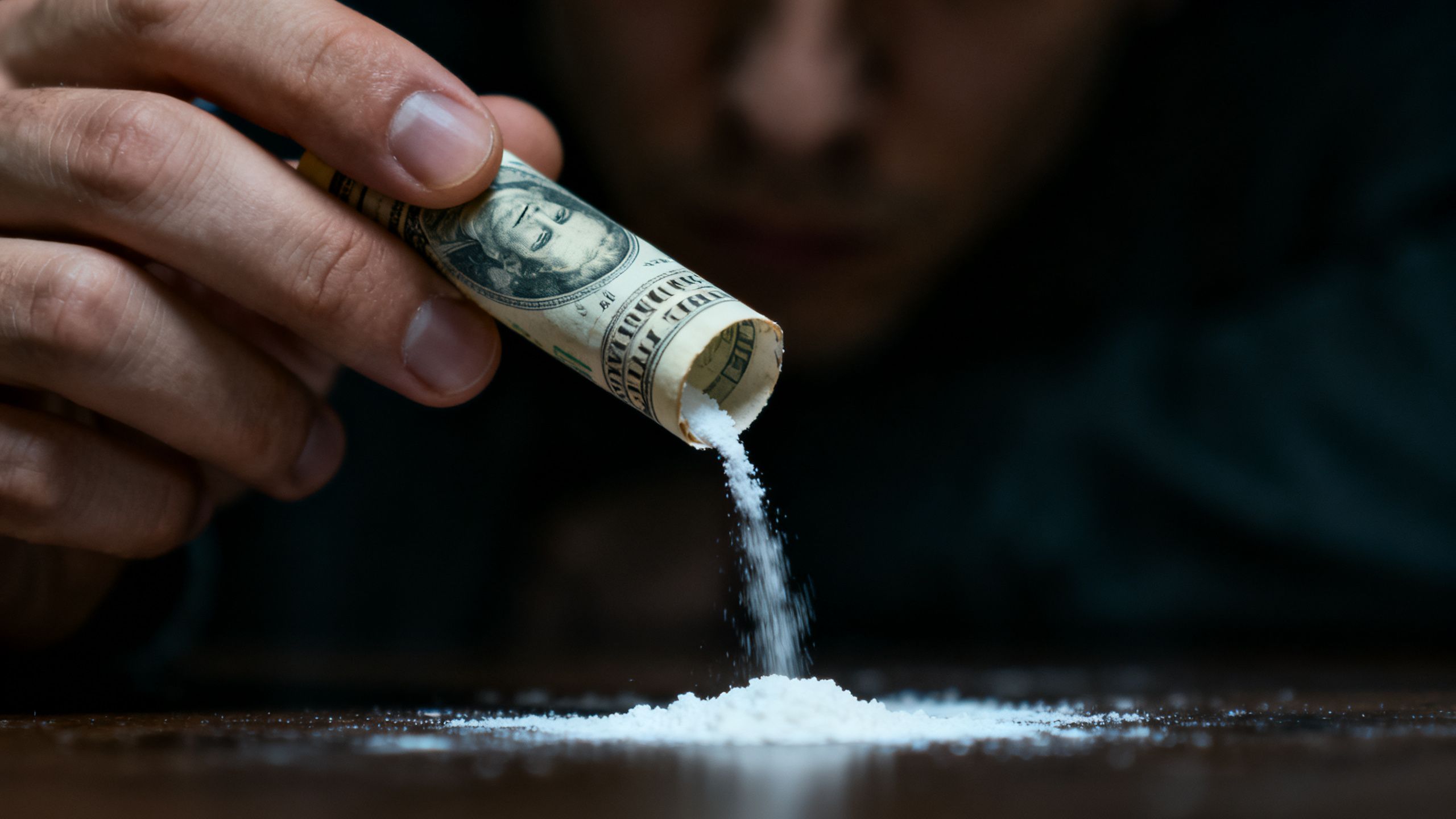 Person preparing to snort cocaine using a rolled banknote.