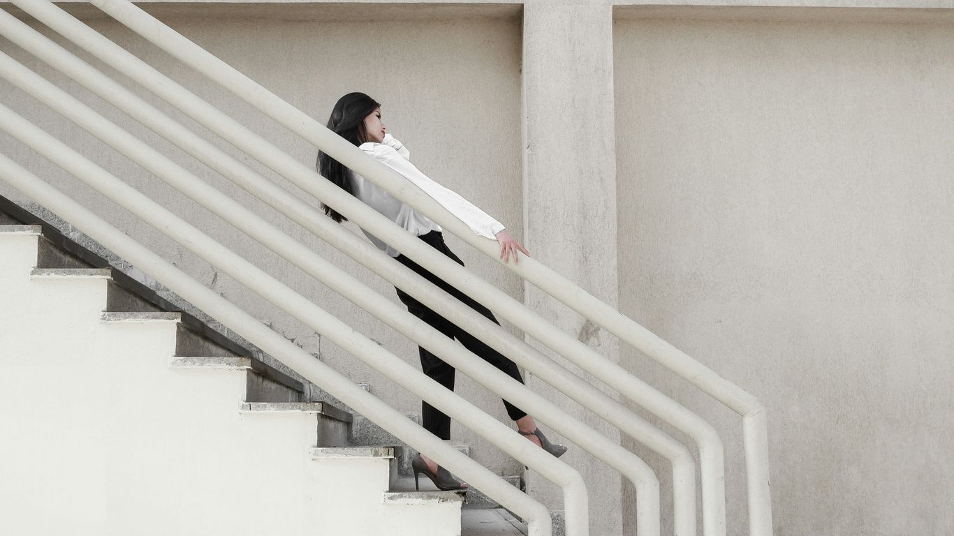 woman in black shirt and black pants sitting on white staircase