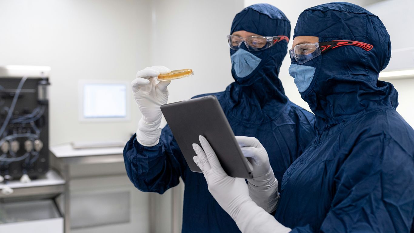 un par de personas con mascarillas y guantes y sosteniendo una tablet