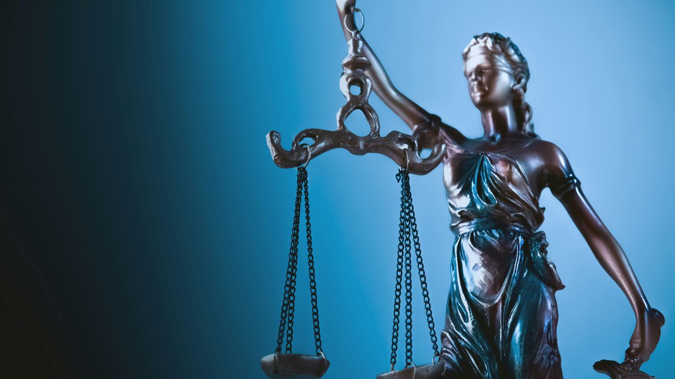 Statue of justice holding scales against blue background
