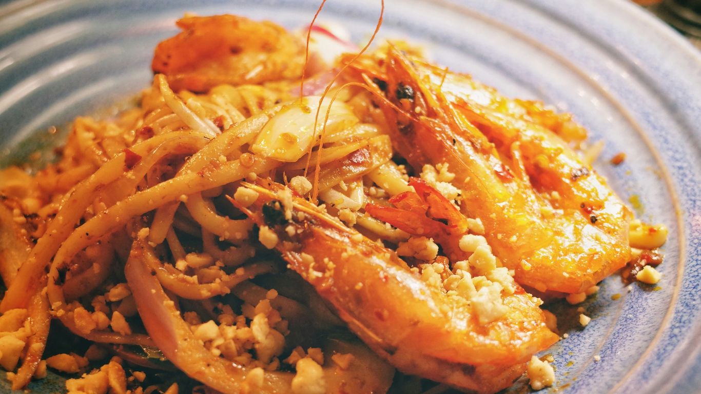a blue plate topped with pasta and shrimp