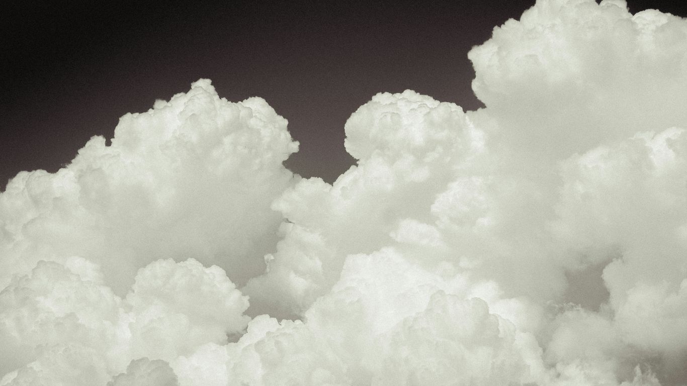 a plane flying through a cloud filled sky