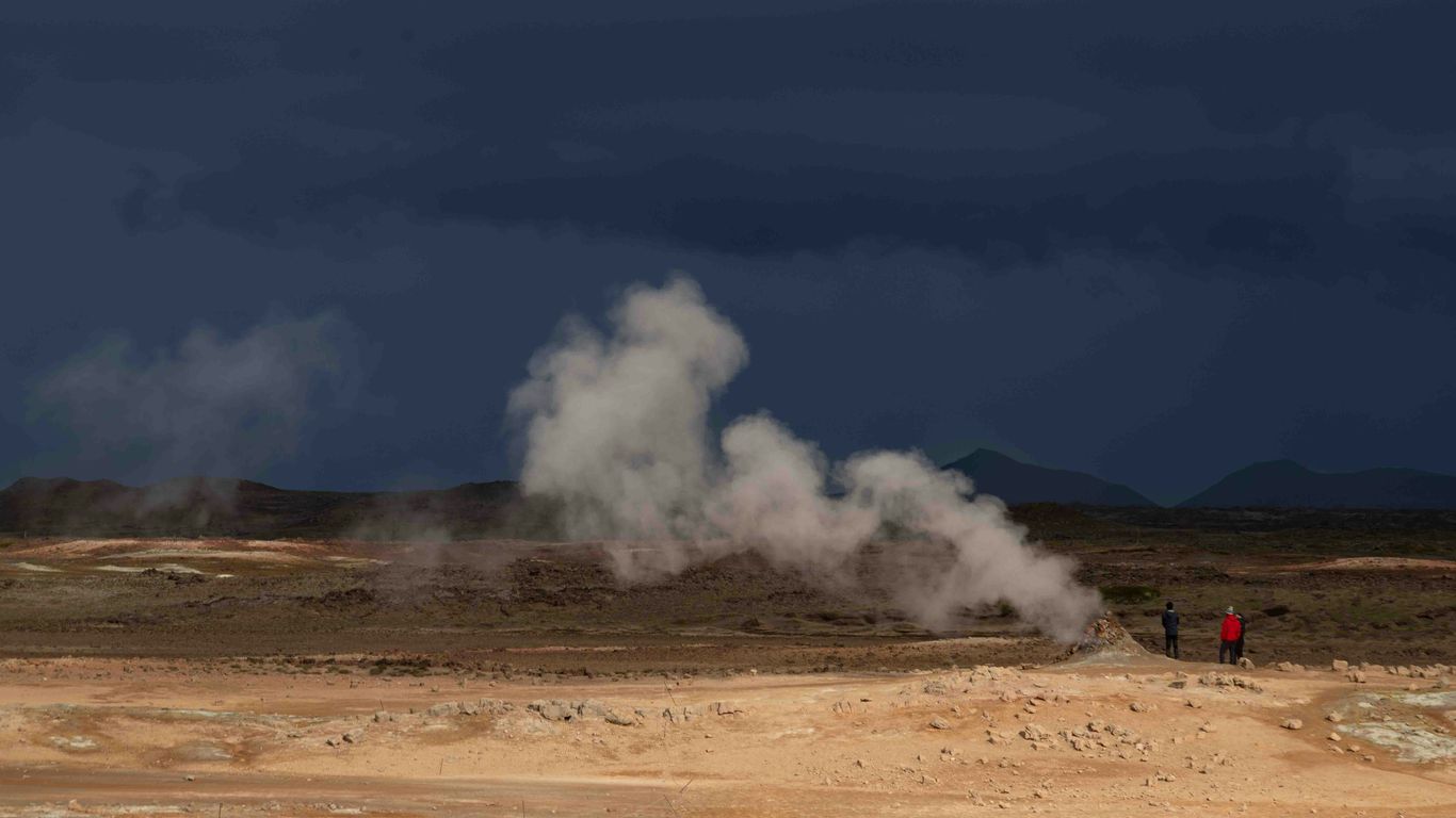 a group of people standing in front of a geyser
