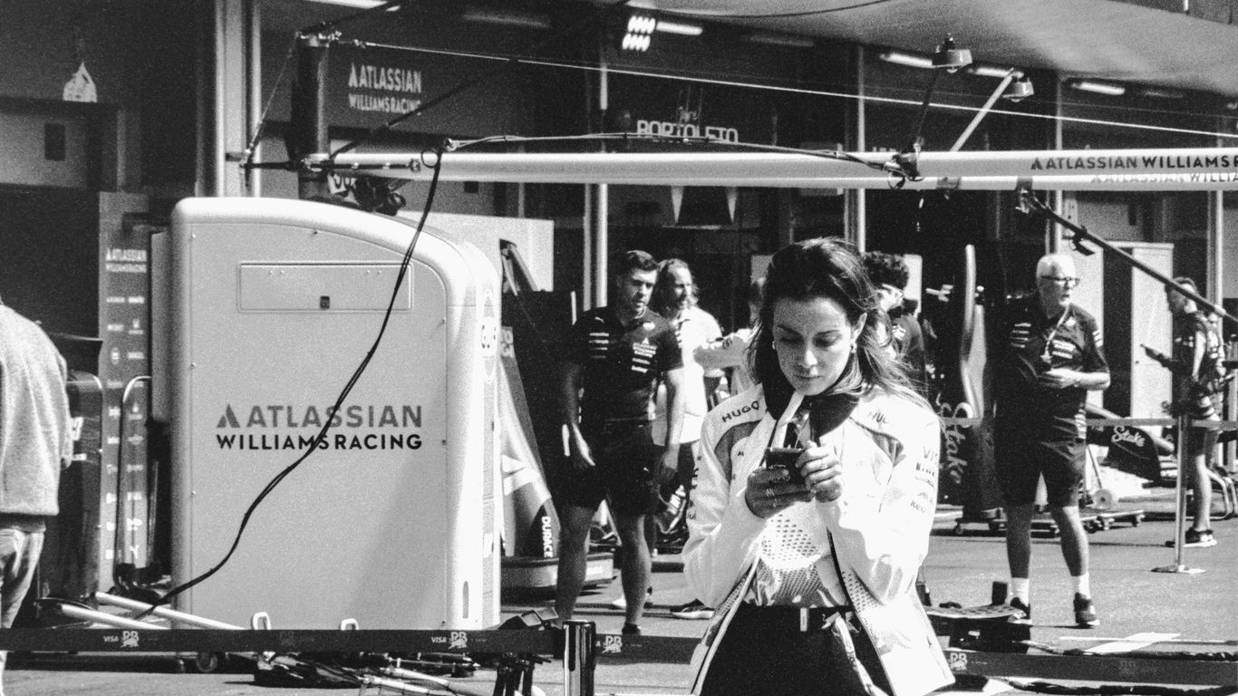 Woman looking at phone near racing pit garage