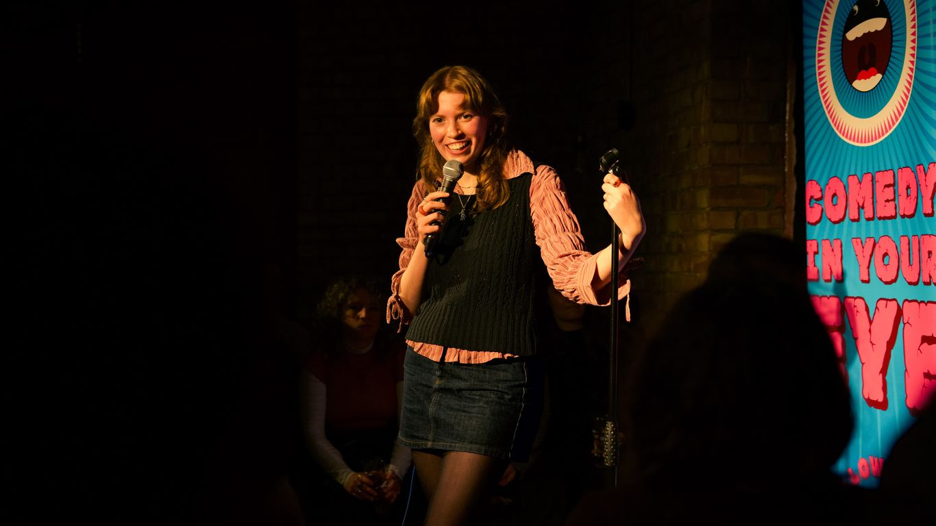 A person performs comedy on stage with a microphone.