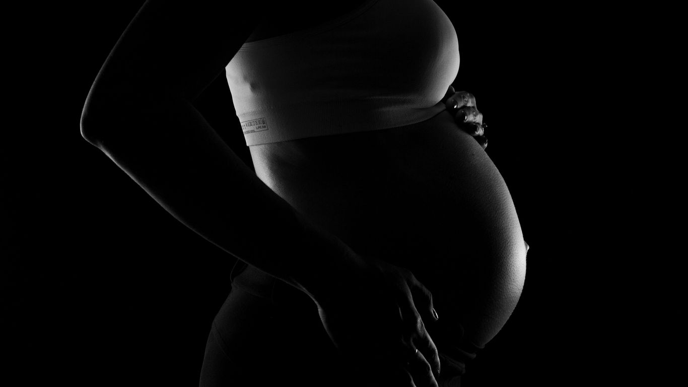 A silhouette of a pregnant person cradling their belly.