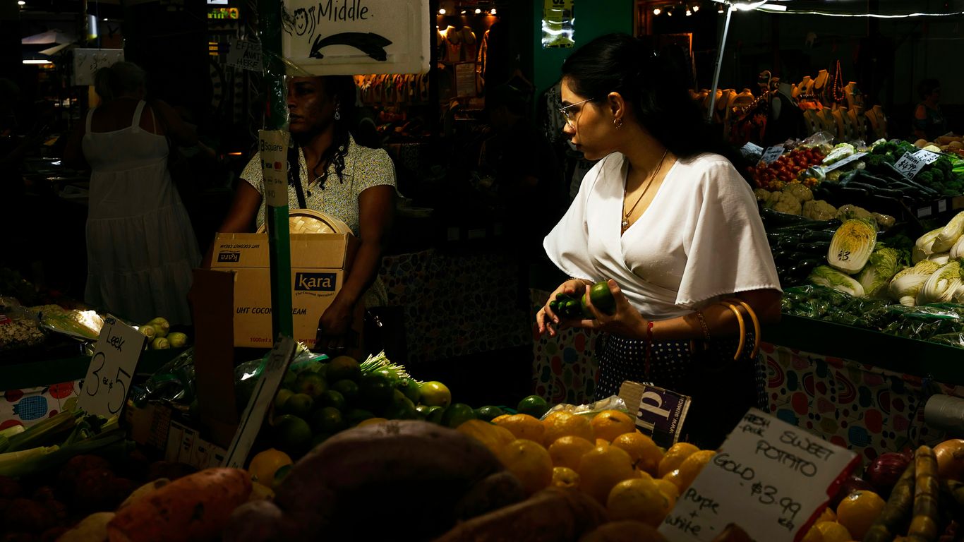 a woman standing in front of a fruit stand