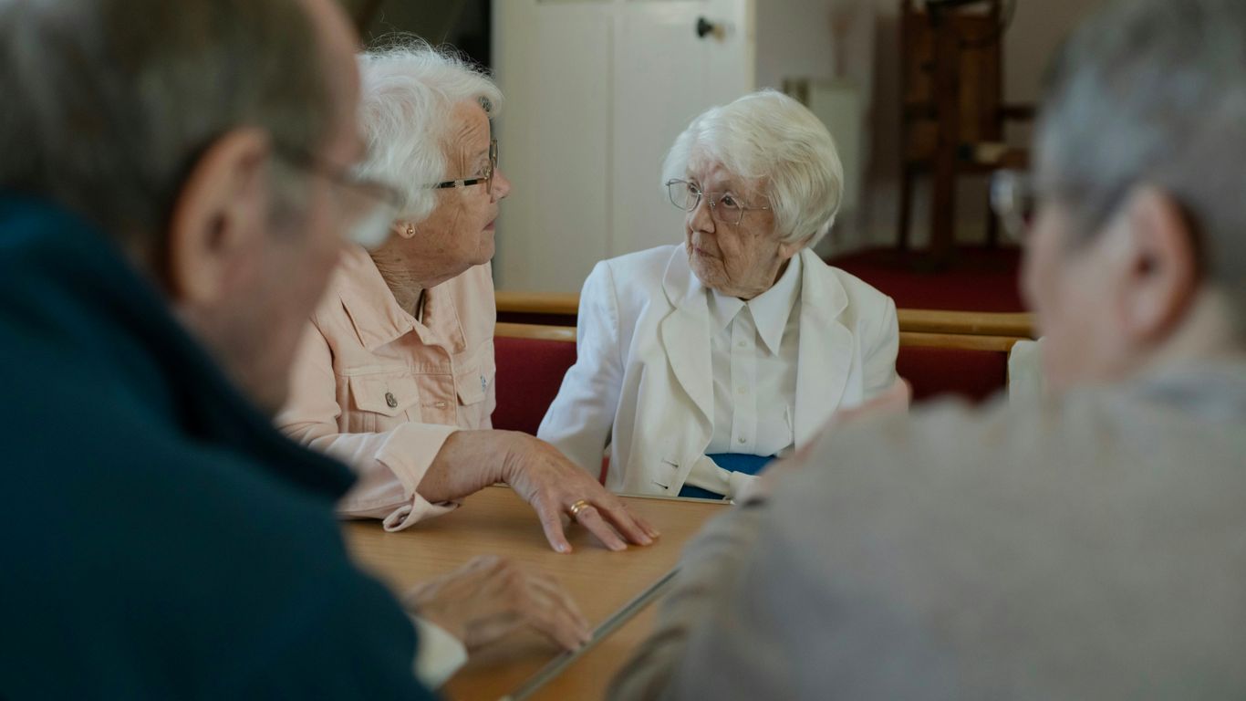 Seniors are sitting around a table, talking.