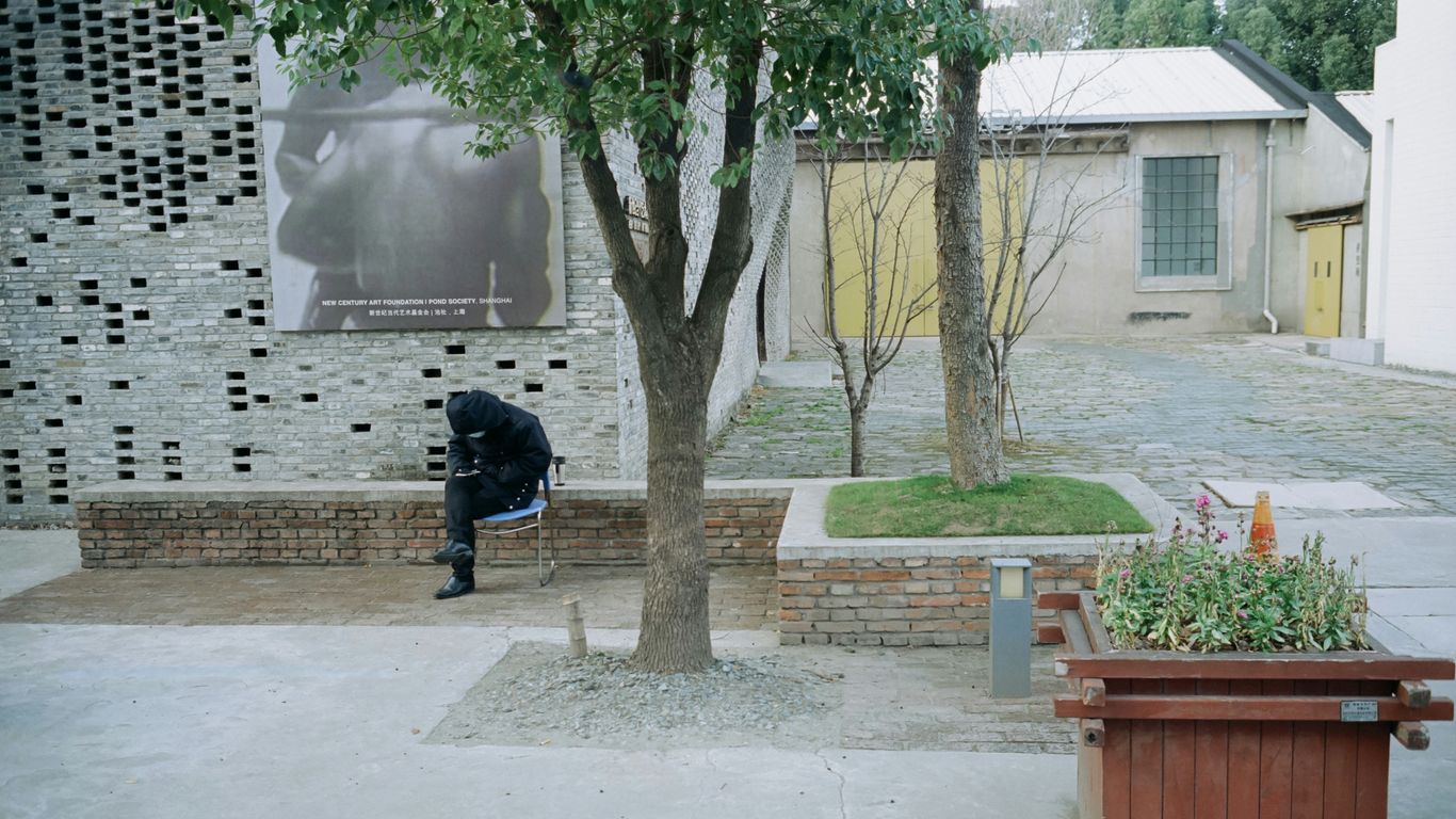 a man sitting on a bench next to a tree
