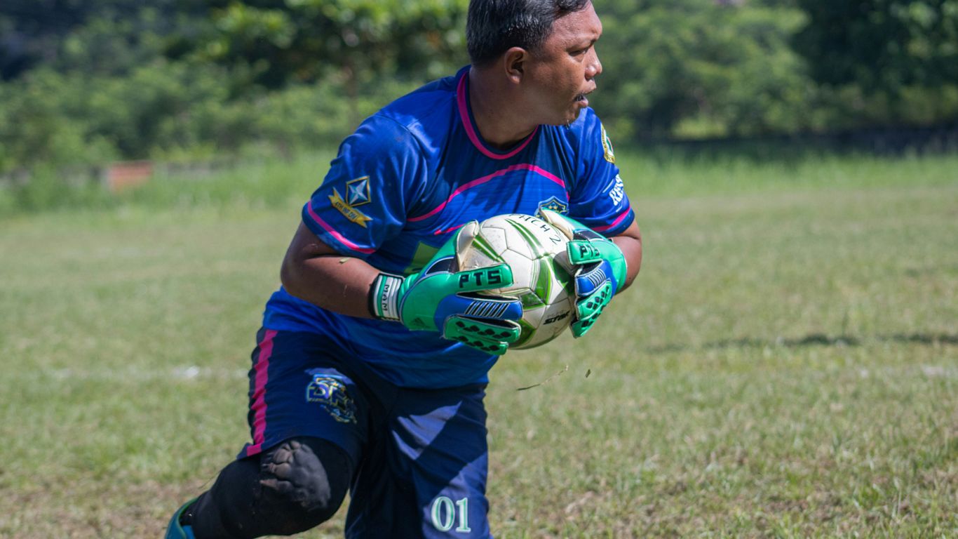 a man holding a soccer ball on top of a field