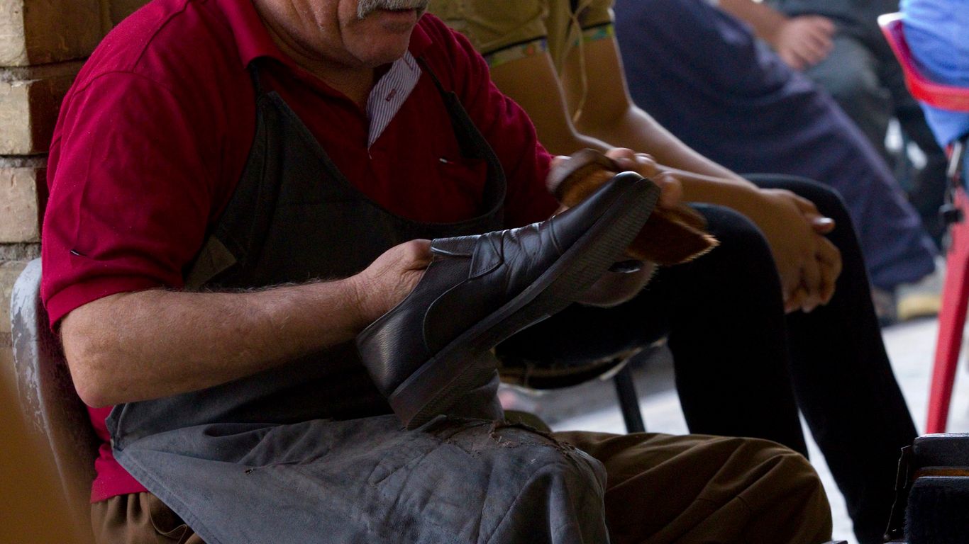 man holding shoe wearing black apron
